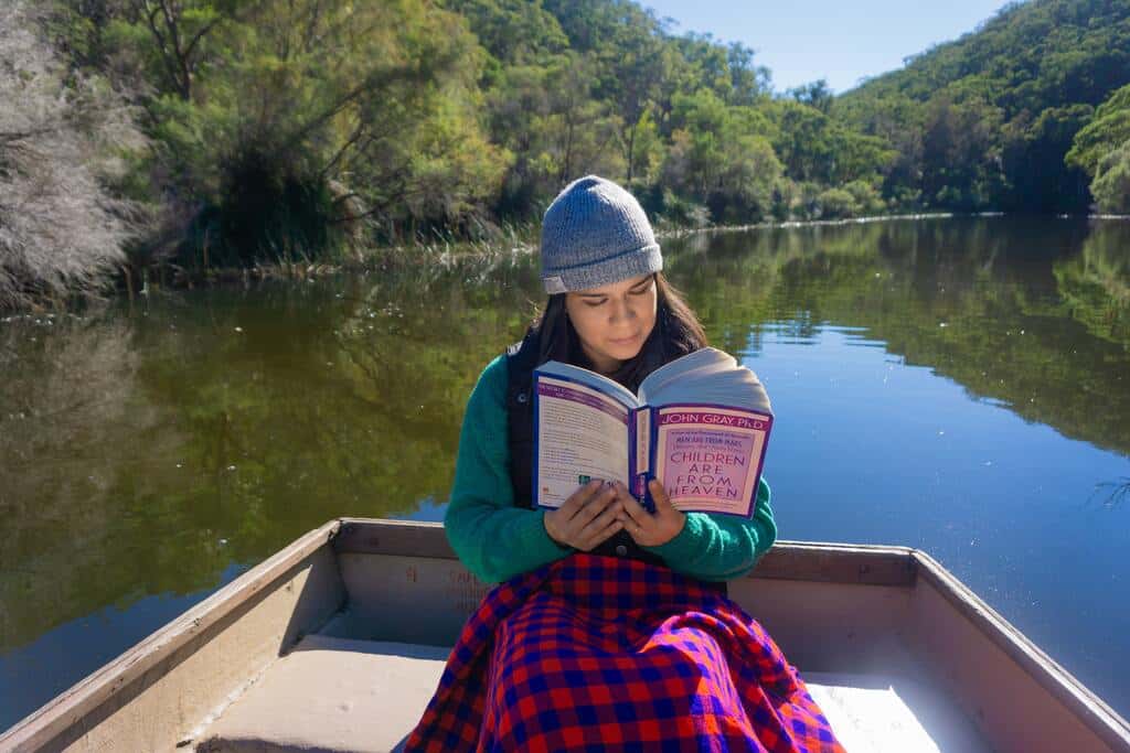 Mulher sentada uma canoa lendo um livro e relaxando