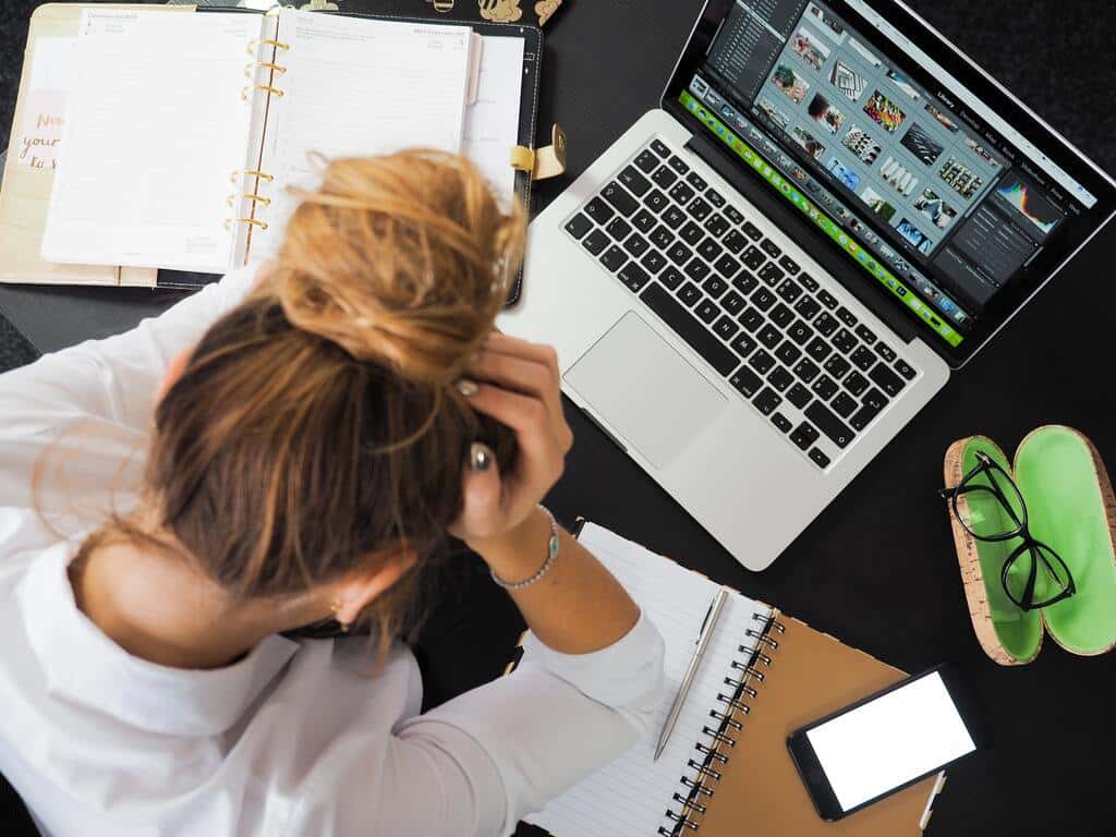 Mulher com as mãos na cabeça olhado para um computador estressada.