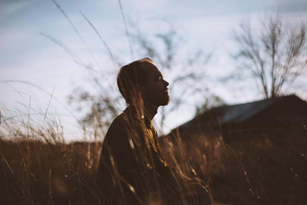 Homem sentado em um campo meditando.