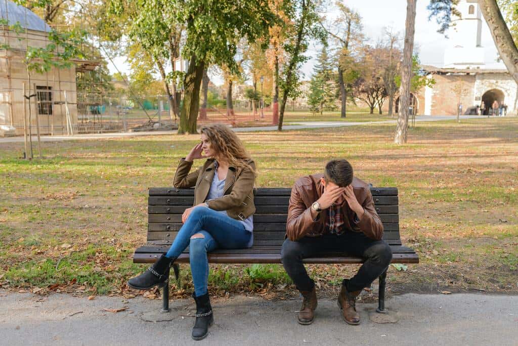 Casal sentado no banco de um parque, separado por conta do stress no relacionamento