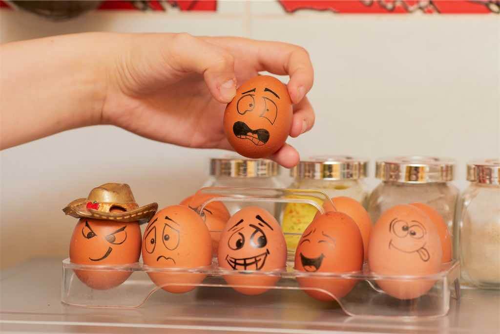 Mão pegando ovos com pintados com emoji