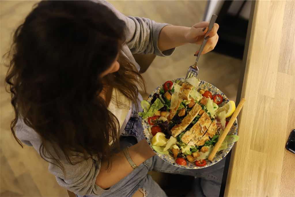 Mulher comendo tiras de frango com salada