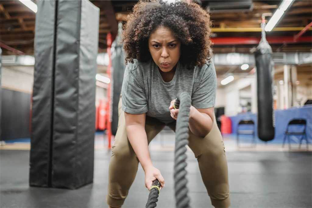 Mulher negra em uma academia fazendo exercícios com cordas