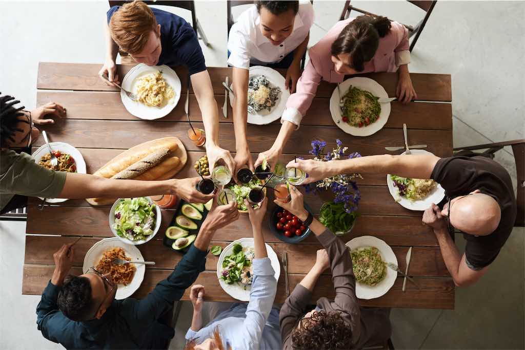 Pessoas sentadas em volta de uma mesa comendo comida saudável