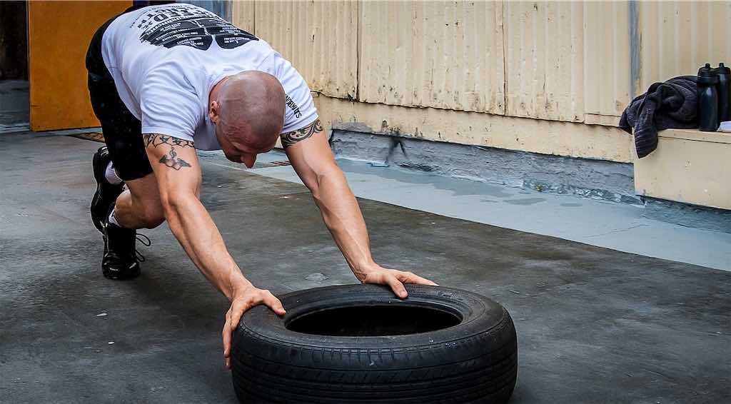 homem empurrando pneu para praticar crossfit